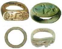 Four rings of various materials and shapes.  Top left:  a gold seal ring with a flat signet bearing the Horus Name of Amenhotep I, Ka-Djoser-Re.  Top right:  another seal ring made out of amazonite (feldspar) with a flat signet bearing the Horus name of Amenhotep III (Neb-Maat-Re).  Bottom left:  a simple tubular ring made of steatite.  Bottom right:  a tubular ring made of steatite with the Eye of Horus carved into the signet.